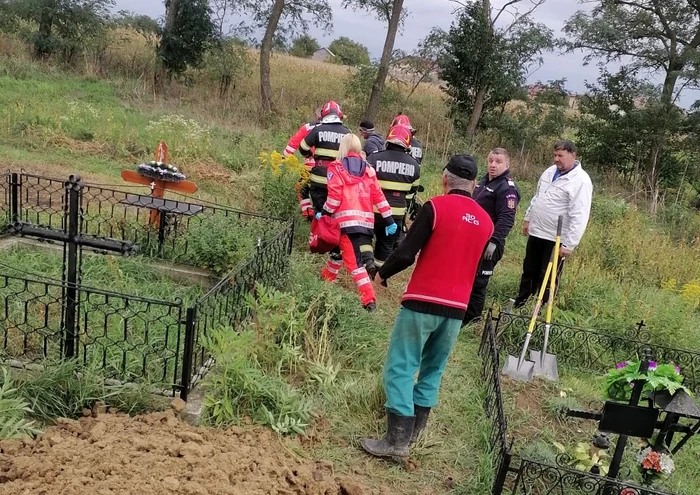 Bărbat care săpa o groapă într-un cimitir, prins sub un mal de pământ